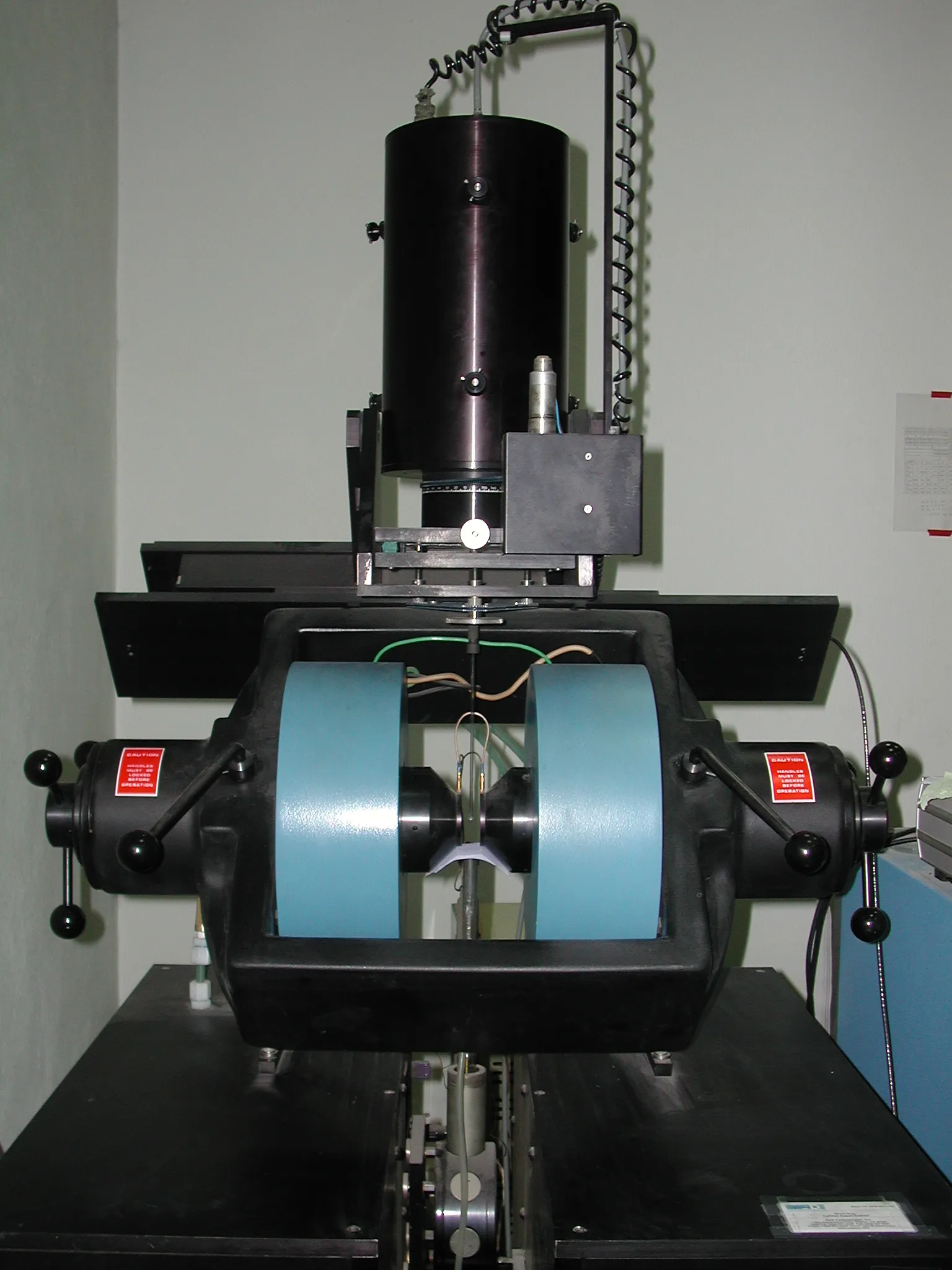 A vibrating-sample magnetometer with electromagnet pole pieces and pickup coils.