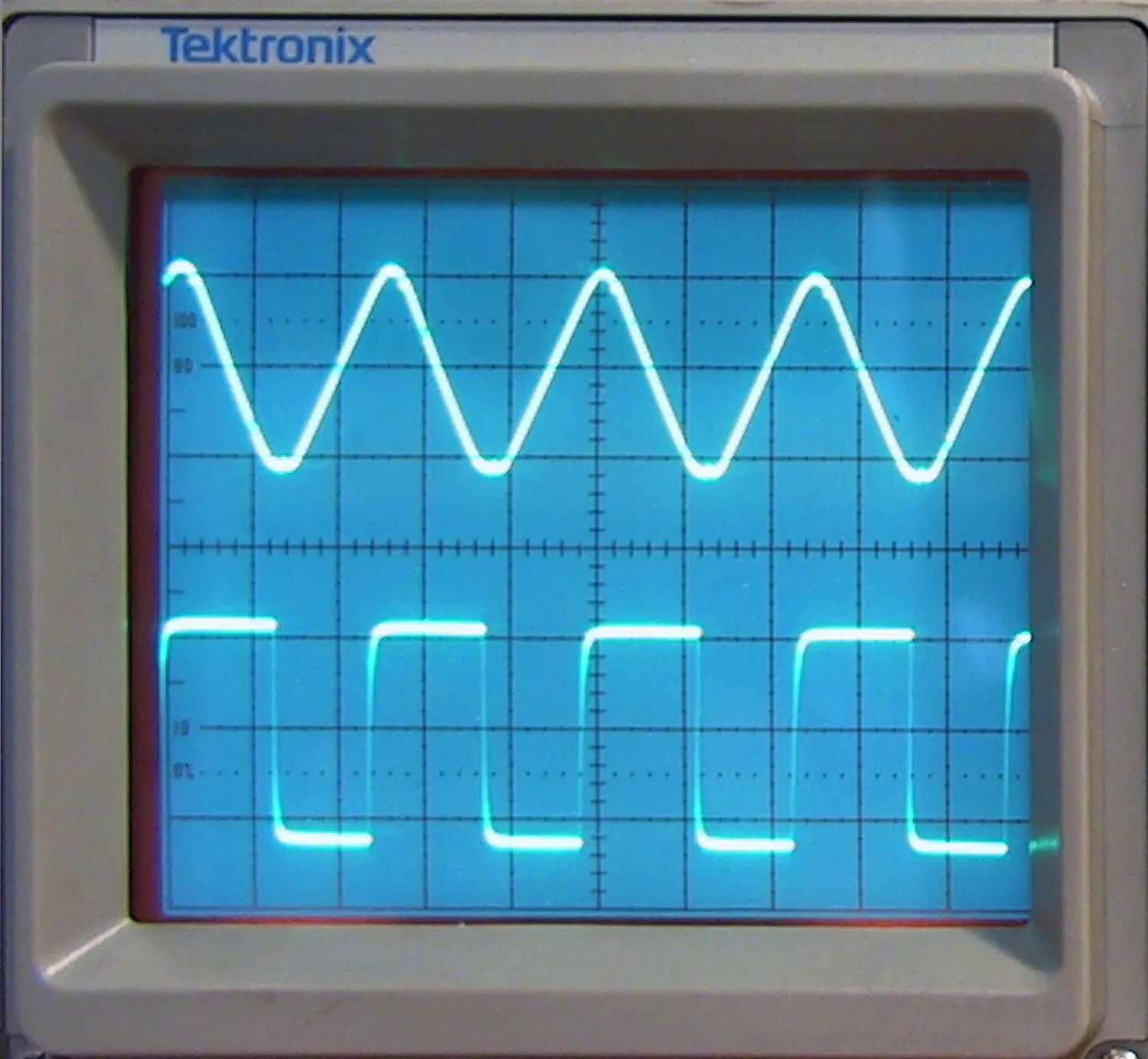 A triangular wave and a square wave on an oscilloscope screen — a periodic signal read off an instrument.